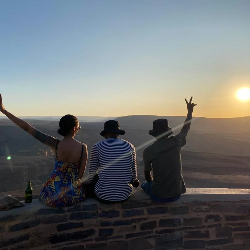 Friends watching the sun set over a vast Namibian canyon